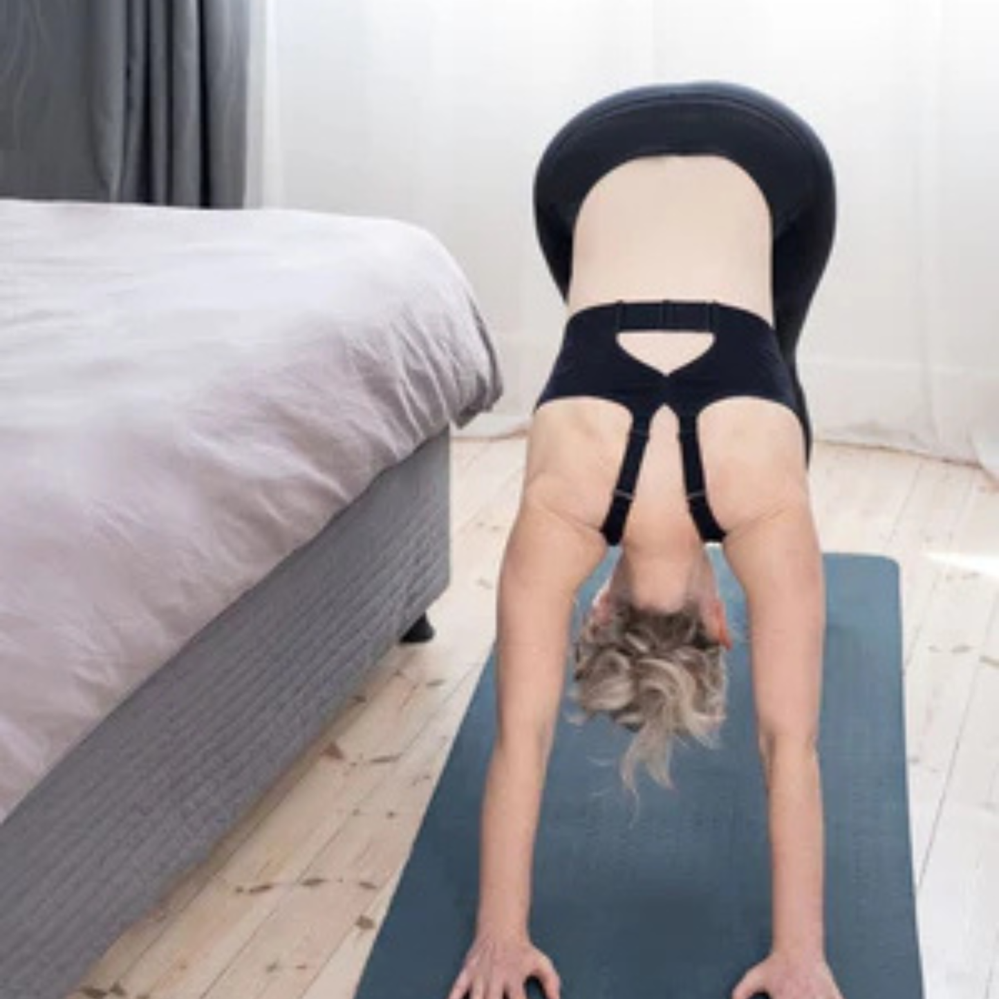 HuggerLUMA compression bra in No Moon Black — worn during yoga, showing low-coverage scoop neckline and keyhole back.