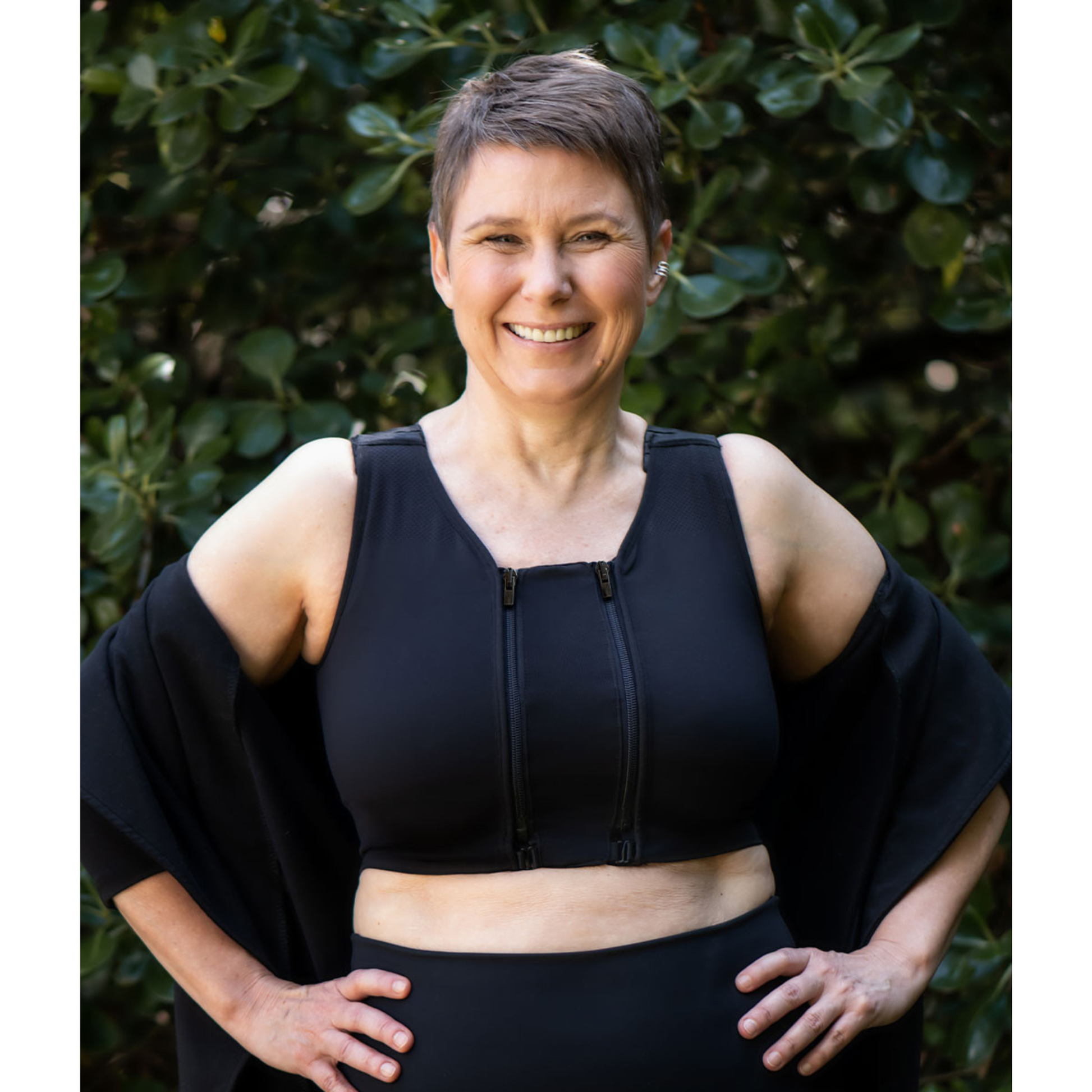 Prairie Wear HuggerPRIMA full-coverage compression bra in black, worn outdoors showing adjustable padded straps and front zip closure.